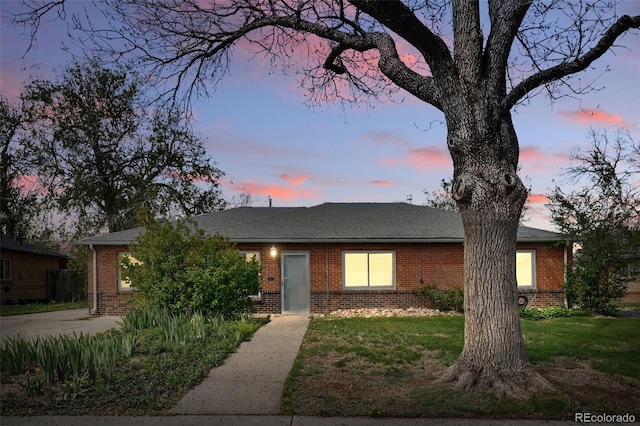 single story home featuring brick siding and a yard