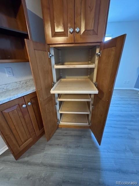 interior space featuring open shelves, wood finished floors, and brown cabinets