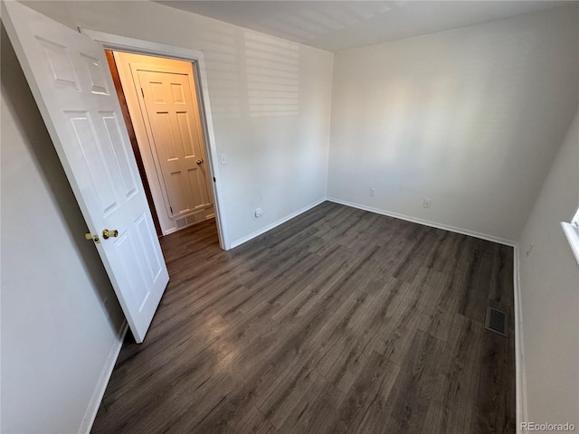 unfurnished room featuring dark wood-style floors, visible vents, and baseboards