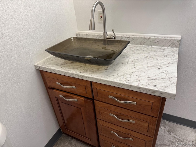 details with a textured wall, vanity, and baseboards