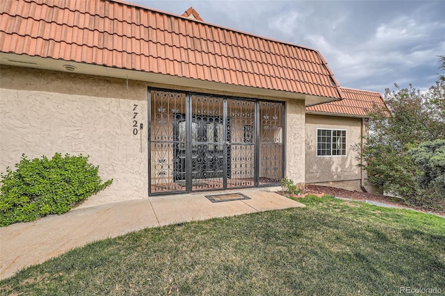 7720 W Quincy Dr, Lakewood, CO 80235 - entrance to property featuring a tile roof, a yard, and stucco siding