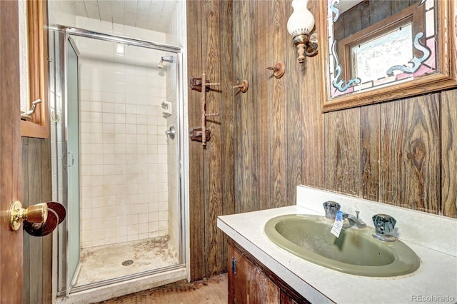 bathroom featuring an enclosed shower, vanity, and wood walls