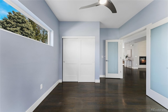 unfurnished bedroom with dark hardwood / wood-style flooring, a closet, and ceiling fan