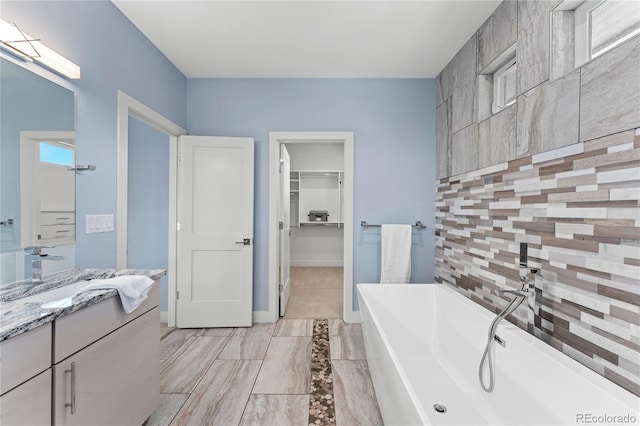 bathroom with vanity, decorative backsplash, and a tub