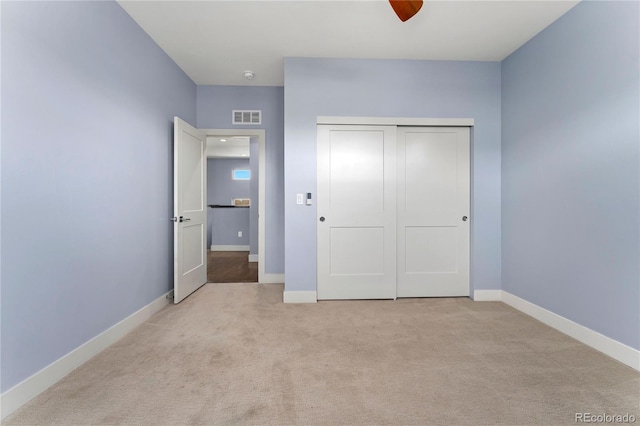 unfurnished bedroom with ceiling fan, a closet, and light colored carpet