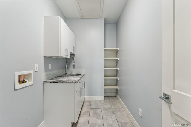 interior space featuring white cabinets, light stone counters, and sink