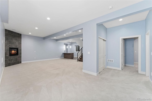 unfurnished living room with a fireplace, light colored carpet, and tile walls