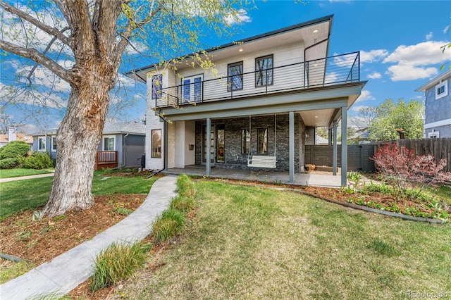 view of front of house with a balcony, a front lawn, and a patio