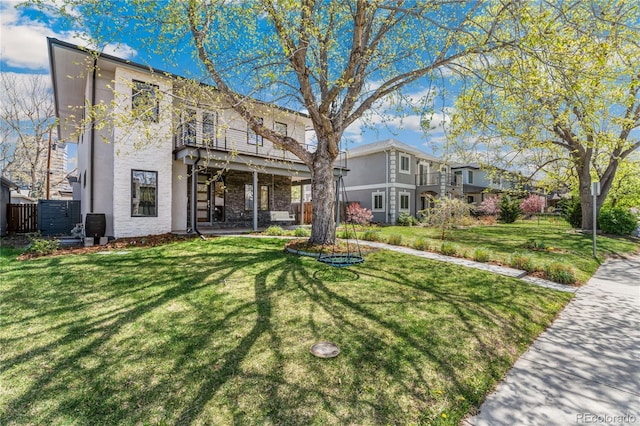 rear view of property with a balcony and a yard