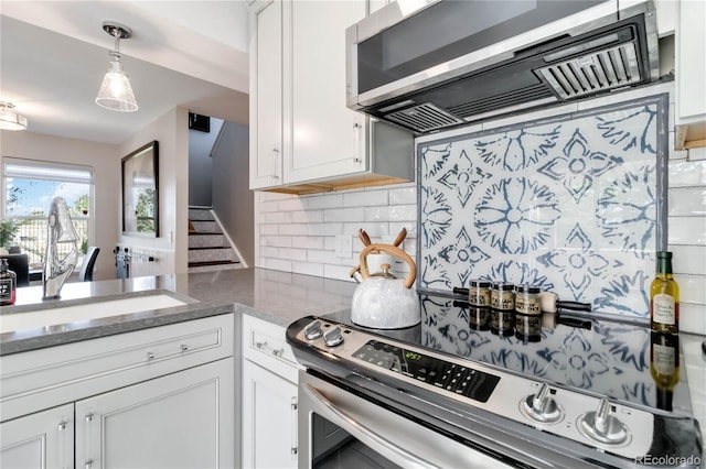 2645 S Xanadu Way Unit D, Aurora, CO 80014 - kitchen with stainless steel appliances, backsplash, white cabinetry, and range hood