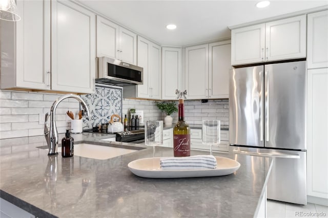 2645 S Xanadu Way Unit D, Aurora, CO 80014 - kitchen featuring appliances with stainless steel finishes, decorative backsplash, dark stone counters, white cabinets, and recessed lighting