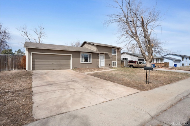 tri-level home featuring a garage, concrete driveway, and fence