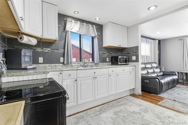 kitchen featuring a healthy amount of sunlight, sink, white cabinets, and light wood-type flooring