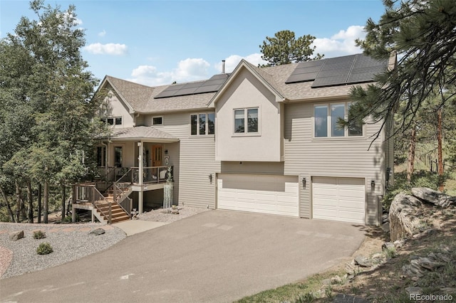 30206 Telluride Ln, Evergreen, CO 80439 - view of front of property featuring covered porch, roof with shingles, an attached garage, driveway, and solar panels