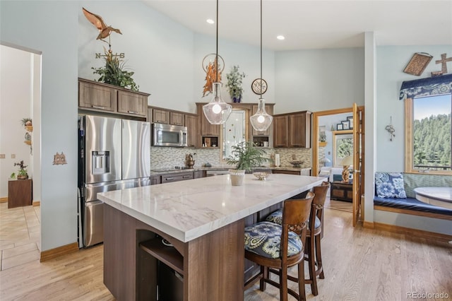 30206 Telluride Ln, Evergreen, CO 80439 - kitchen with stainless steel appliances, a kitchen island, decorative backsplash, light stone countertops, and decorative light fixtures
