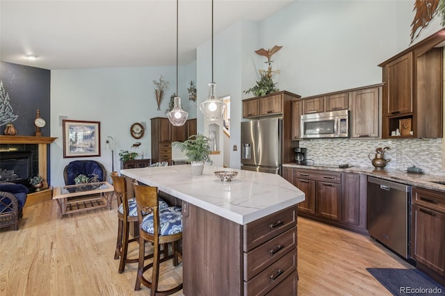 30206 Telluride Ln, Evergreen, CO 80439 - kitchen with stainless steel appliances, light wood-style floors, a kitchen island, a kitchen bar, and a towering ceiling