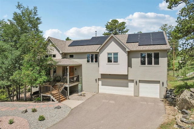 30206 Telluride Ln, Evergreen, CO 80439 - view of front of property featuring a porch, a shingled roof, driveway, an attached garage, and solar panels