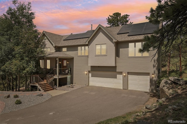30206 Telluride Ln, Evergreen, CO 80439 - view of front of home with asphalt driveway, a garage, roof with shingles, covered porch, and solar panels