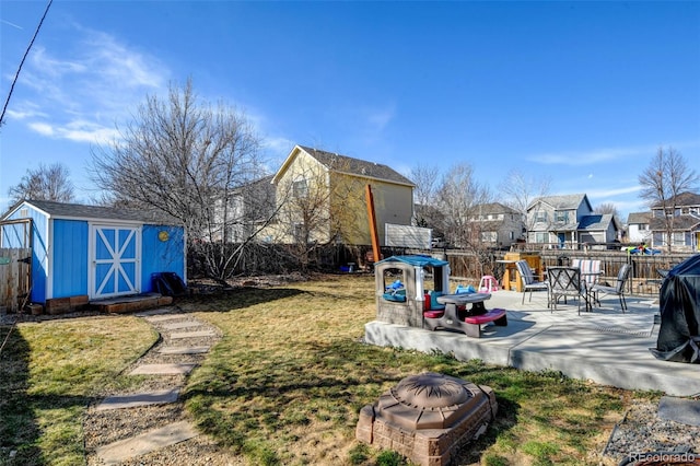 view of yard with a patio, a storage shed, a fenced backyard, and an outdoor fire pit