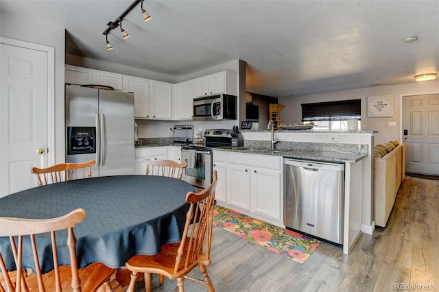 kitchen featuring a sink, stainless steel appliances, light wood-type flooring, and a peninsula