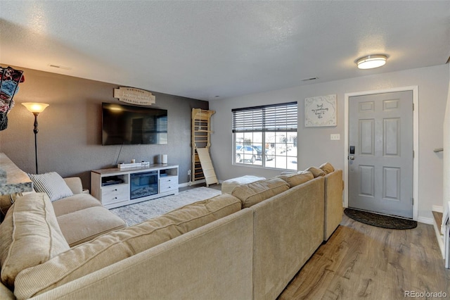 living area featuring a textured ceiling, baseboards, and wood finished floors