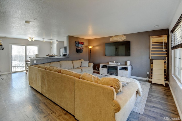 living room with a textured ceiling, baseboards, and wood finished floors