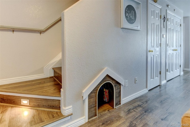 stairway with a textured wall, baseboards, and wood finished floors