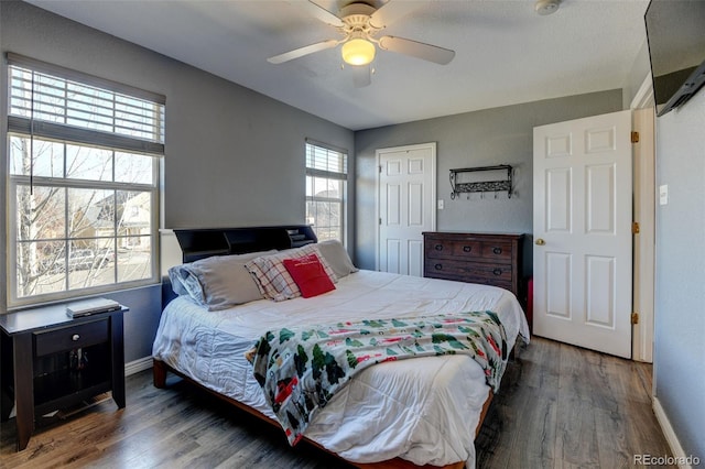 bedroom featuring a closet, baseboards, wood finished floors, and a ceiling fan