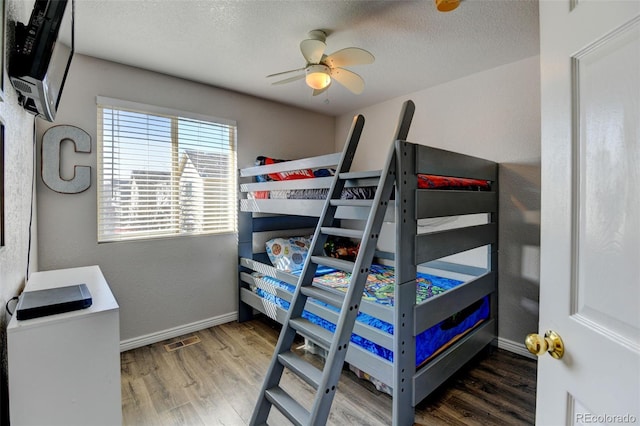 bedroom featuring visible vents, a ceiling fan, a textured ceiling, wood finished floors, and baseboards