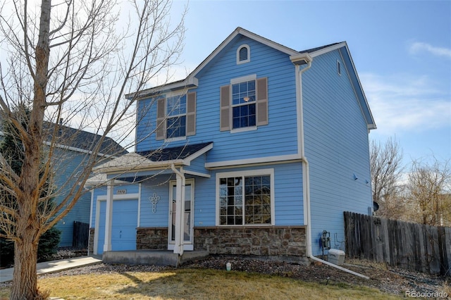 traditional-style house with stone siding, concrete driveway, a garage, and fence