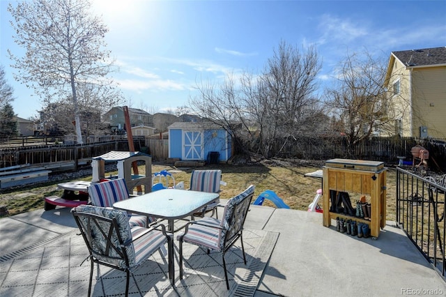 view of patio / terrace with a storage unit, a fenced backyard, an outdoor structure, and outdoor dining space