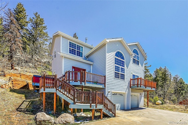 11770 Leavenworth Dr, Conifer, CO 80433 - rear view of house featuring stairs, a garage, a wooden deck, and driveway