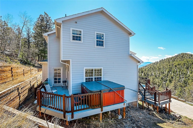 11770 Leavenworth Dr, Conifer, CO 80433 - back of house with a hot tub, a deck, and a view of trees