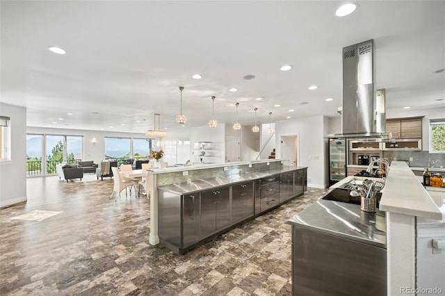 kitchen with island exhaust hood, hanging light fixtures, backsplash, and a spacious island