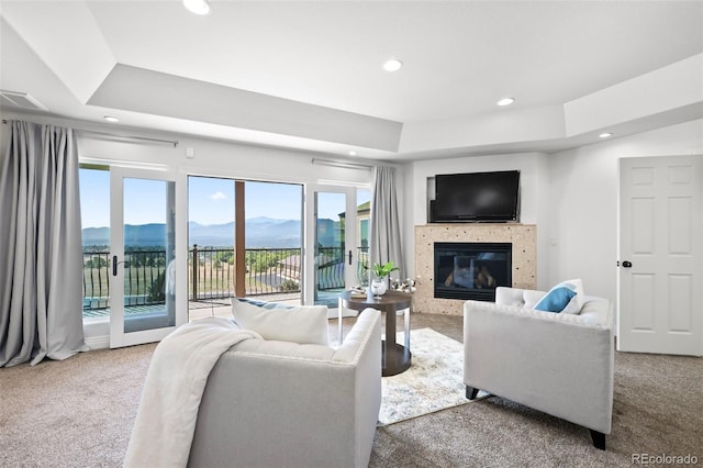 living room with a tray ceiling and carpet flooring