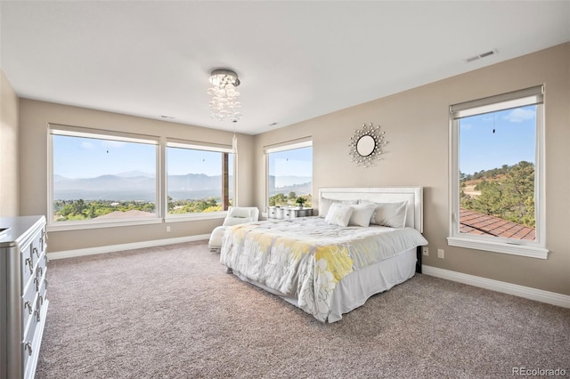 carpeted bedroom featuring a mountain view, an inviting chandelier, and multiple windows