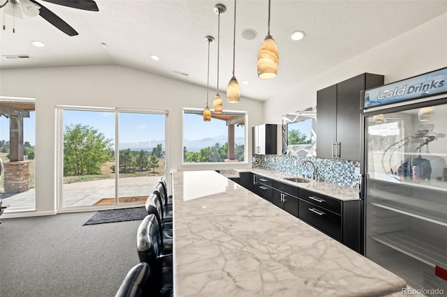 kitchen featuring pendant lighting, lofted ceiling, carpet, backsplash, and ceiling fan