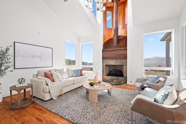 living room featuring high vaulted ceiling, a tiled fireplace, a mountain view, and hardwood / wood-style flooring