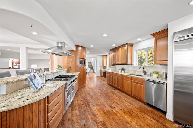 kitchen with sink, wall chimney range hood, dark hardwood / wood-style floors, high quality appliances, and decorative backsplash