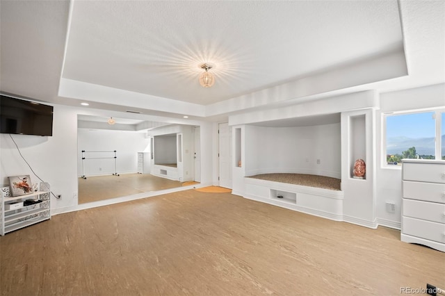 unfurnished living room featuring a raised ceiling and hardwood / wood-style floors