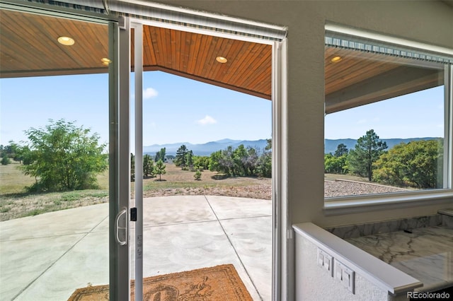 doorway to outside featuring wood ceiling, lofted ceiling, a mountain view, and a wealth of natural light