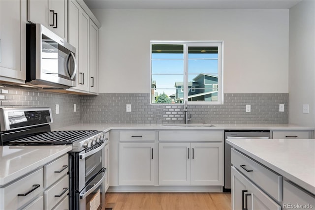 kitchen with white cabinets, sink, tasteful backsplash, light hardwood / wood-style flooring, and stainless steel appliances