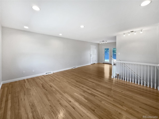 spare room with hardwood / wood-style flooring, track lighting, and french doors