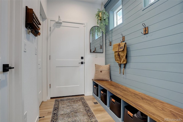 mudroom featuring light hardwood / wood-style flooring and wood walls