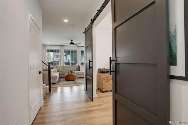 hall with a barn door and light wood-type flooring