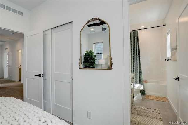 bedroom with a closet, connected bathroom, and light tile patterned flooring