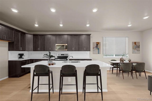 kitchen with stainless steel appliances, sink, a breakfast bar, and a kitchen island with sink