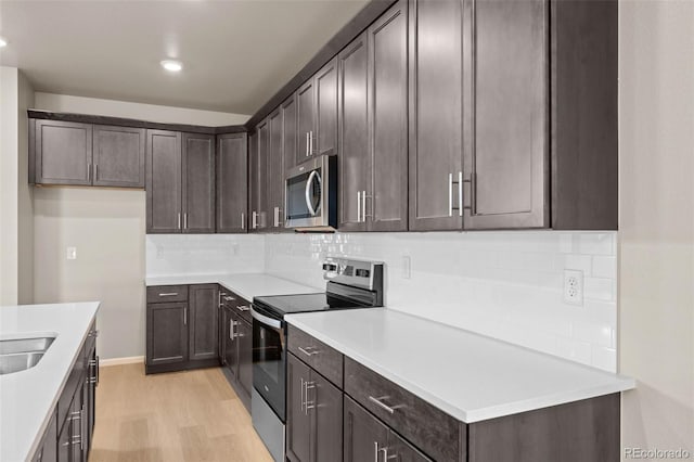 kitchen with tasteful backsplash, dark brown cabinetry, appliances with stainless steel finishes, and light hardwood / wood-style flooring