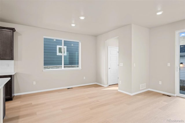 unfurnished living room featuring plenty of natural light and light hardwood / wood-style flooring