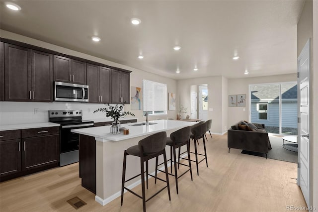 kitchen featuring sink, a breakfast bar, a kitchen island with sink, stainless steel appliances, and light hardwood / wood-style floors